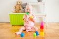 Little baby girl sitting on the floor, crawling and playing with brightly colored educational toys