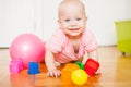 Little baby girl sitting on the floor, crawling and playing with brightly colored educational toys