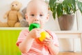 Little baby girl sitting on the floor, crawling and playing with brightly colored educational toys