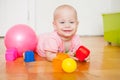 Little baby girl sitting on the floor, crawling and playing with brightly colored educational toys