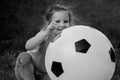 Little baby girl sitting with a huge ball of football colors. Royalty Free Stock Photo