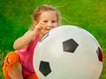 Little baby girl sitting with a huge ball of football colors. Royalty Free Stock Photo