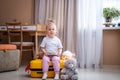 Little baby girl sitting on yellow suitcase baggage luggage, family ready to go for traveling on vacation at home