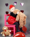 Little baby girl toddler sitting on small pink chair with bear toy in studio Royalty Free Stock Photo