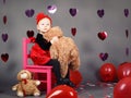 Little baby girl toddler sitting on small pink chair with bear toy in studio Royalty Free Stock Photo