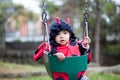 Little baby girl wearing a ladybug costume sitting on a toddler Swing. Halloween concept
