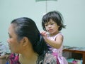Little baby girl, 2 years old, enjoys playing / pretending to do her auntie`s hairs at home