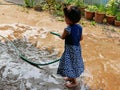 Little baby girl, 3 years old, standing on wet ground and playing water freely by herself Royalty Free Stock Photo