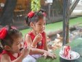 Little baby girls, sisters, enjoys eating a rainbow crepe cake with strawberry sauce on top at a restaurant