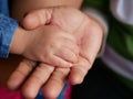 Little baby hand in her grandmother`s hand representing grandparent-grandchild bond and relationship