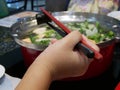 Little baby hand holding chopsticks learning to use it to pick food from a hot pot Royalty Free Stock Photo