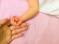 Little baby hand in mothers hands. Pink background. Royalty Free Stock Photo