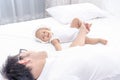 Little baby infant girl laying on white bed smiling to her daddy. Family having a happy time together Royalty Free Stock Photo
