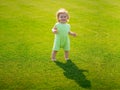 Little baby learning to crawl steps on the grass. Concept childrens months. Happy child playing on green grass
