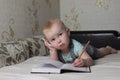 little baby lying on the couch and writing in a notebook pen Royalty Free Stock Photo