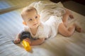 Little baby 8 months Lies on a white bed. infant girl plays with the action camera and looking at mom