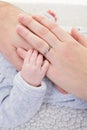 Little baby Newborn boy in grey pajamas holding mother father hand on bed in close up Royalty Free Stock Photo