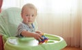 Little baby playing toy car sitting in highchair