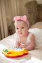 Little baby playing with toy at home. happy child girl laying on bed in nursery. 8 months baby girl Royalty Free Stock Photo