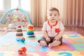 Little baby playing with toys on playmat at home.