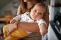 A little baby posing for a photo in mother`s arms at home. Family, parenting, home Royalty Free Stock Photo