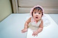 Little Baby Princess girl wear white dress with whit hood lying down on pad floor. Looking at camera Royalty Free Stock Photo