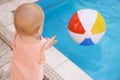 Little baby reaching for inflatable ball at swimming pool. Dangerous situation Royalty Free Stock Photo