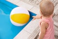 Little baby reaching for inflatable ball at swimming pool. Dangerous situation Royalty Free Stock Photo