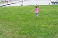 Little baby running on the grass against the background of a modern city Royalty Free Stock Photo