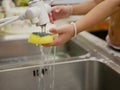 Little baby`s hand holding dishwashing sponge soaking in water, as she was washing kitchen sink by herself Royalty Free Stock Photo