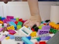 Little baby`s hand picking / choosing a piece of colorful interlocking plastic bricks