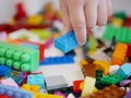 Little baby`s hand picking / choosing a piece of colorful interlocking plastic bricks