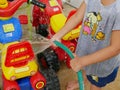 Little baby`s hands playing water and learning to wash plastic big bikes