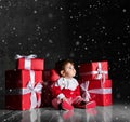 Little baby babe with santa costume with red boxes on a dark background Royalty Free Stock Photo