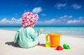 Little baby sits on a tropical beach and plays Royalty Free Stock Photo