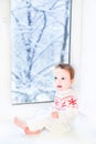 Little baby sitting at window to snowy garden Royalty Free Stock Photo