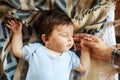 Little baby sleeping calm in bed at home, mother holding the hand, blue and white blanket background