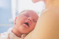 Little baby sleeps with open mouth snuggling to mom`s chest