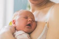 Little baby sleeps with open mouth snuggling to mom`s chest