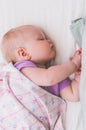 Little baby sleeps sweetly lying on its side with arms folded together Royalty Free Stock Photo