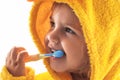 Little baby smiling under a yellow towel and brushing his teeth Royalty Free Stock Photo