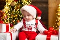 Little baby wearing Santa hat. Cute baby face near Christmas tree. Happy Childhood, child one year. New year kids. Royalty Free Stock Photo