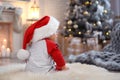 Little baby wearing Santa hat on floor. First Christmas