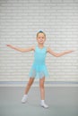 Little ballerina in blue dress and pointe shoes is dancing in ballet school. Cute girl in dance class.