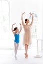 The little ballerina posing at ballet barre with personal teacher in dance studio