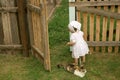 A little barefoot girl in a white dress stands next to the yard cats Royalty Free Stock Photo