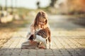 A little barefooted girl in a gray linen dress is stroking a cat. Sunny summer evening in the village. Countryside Royalty Free Stock Photo