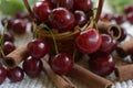 Little basket with handle, red cherries cinnamon rods on white Royalty Free Stock Photo