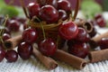 Red cherries with stems and cinnamon rods on white tablecloth Royalty Free Stock Photo