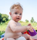 Little beautiful baby girl sitting on the grass on the nature and drinking water from his bottle Royalty Free Stock Photo